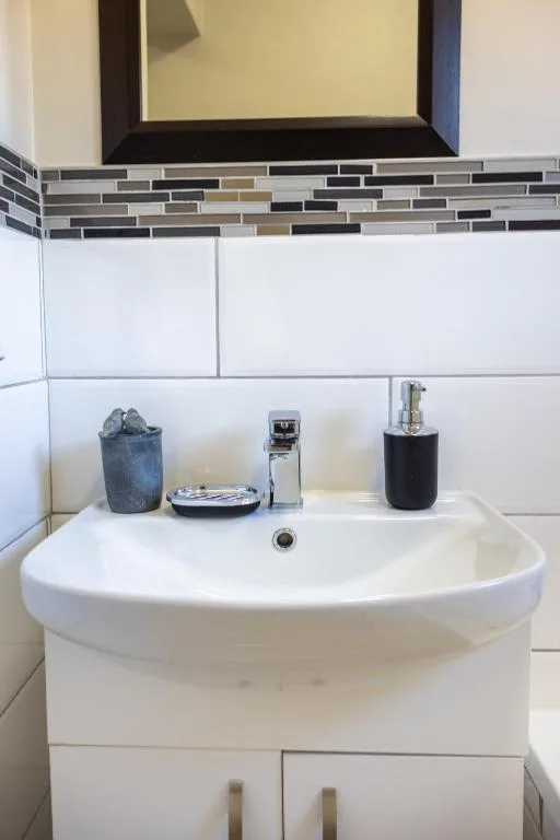 Modern bathroom sink with white vanity and geometric tile backsplash