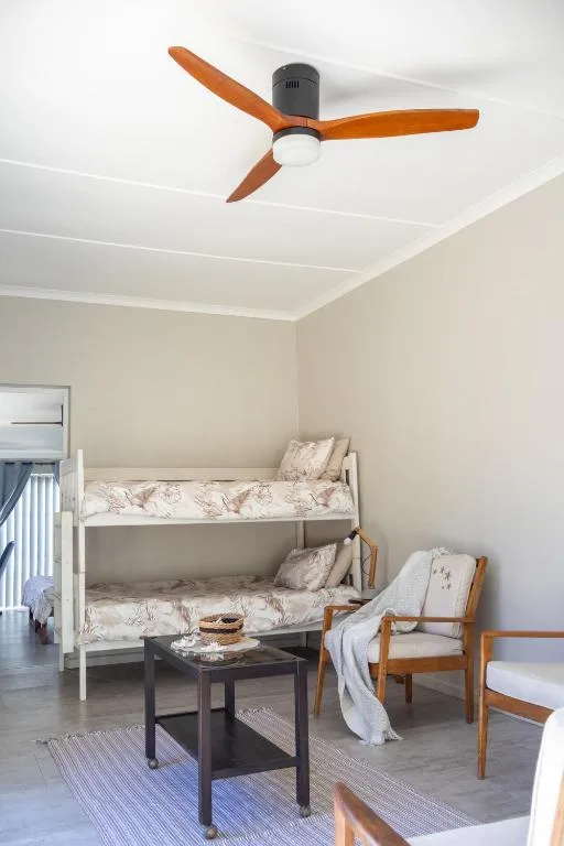 Bright bedroom with bunk beds, wooden chairs, and ceiling fan