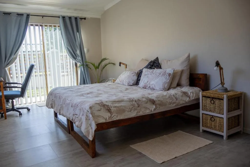Spacious bedroom with wooden bed, patterned bedding, and glass doors to balcony