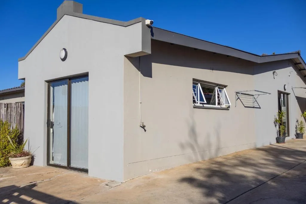 Modern white and cream beach cottage with glass doors and windows under blue sky