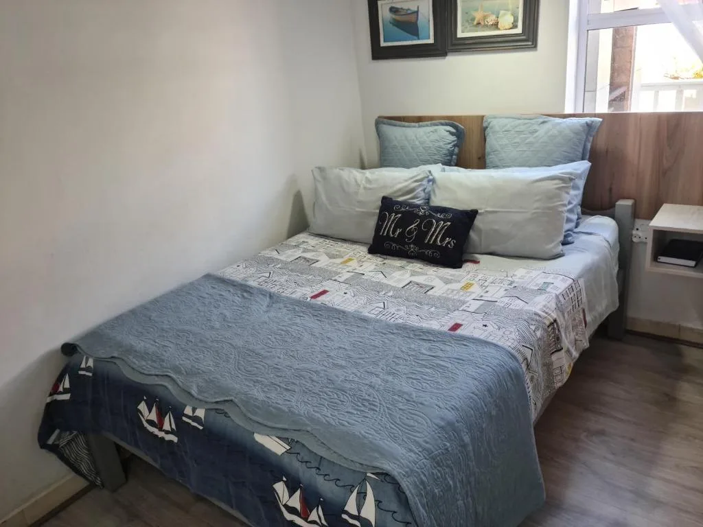 Comfortable double bed with blue and white bedding and decorative pillows