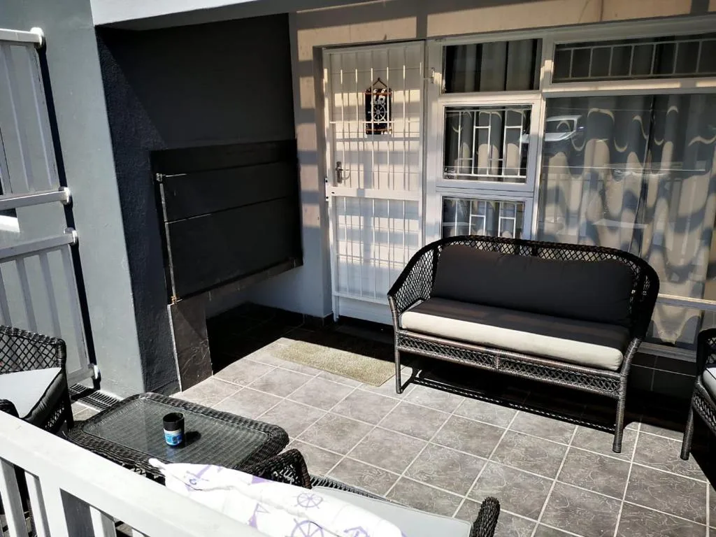 Modern patio with black wicker seating and tiled flooring overlooking property