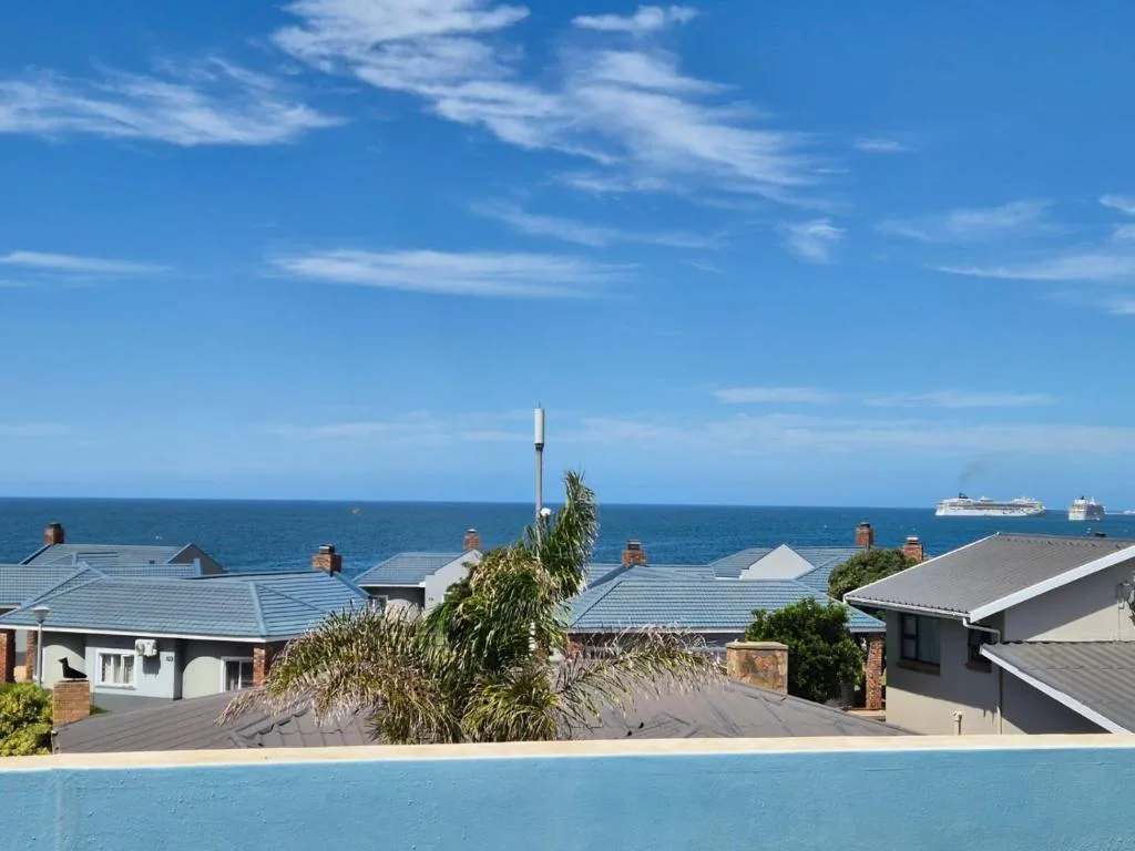 Ocean vista with cruise ships and coastal homes under blue sky