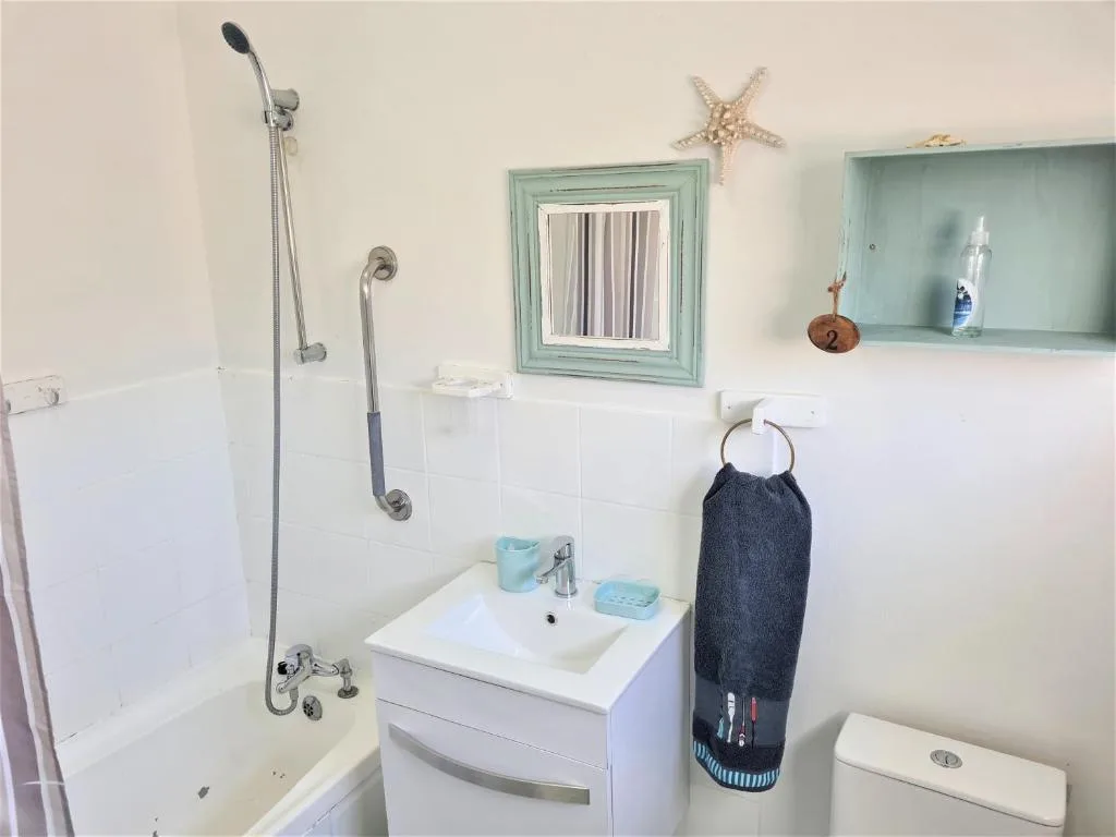 Bright bathroom with white vanity, shower, and coastal-themed wall decor