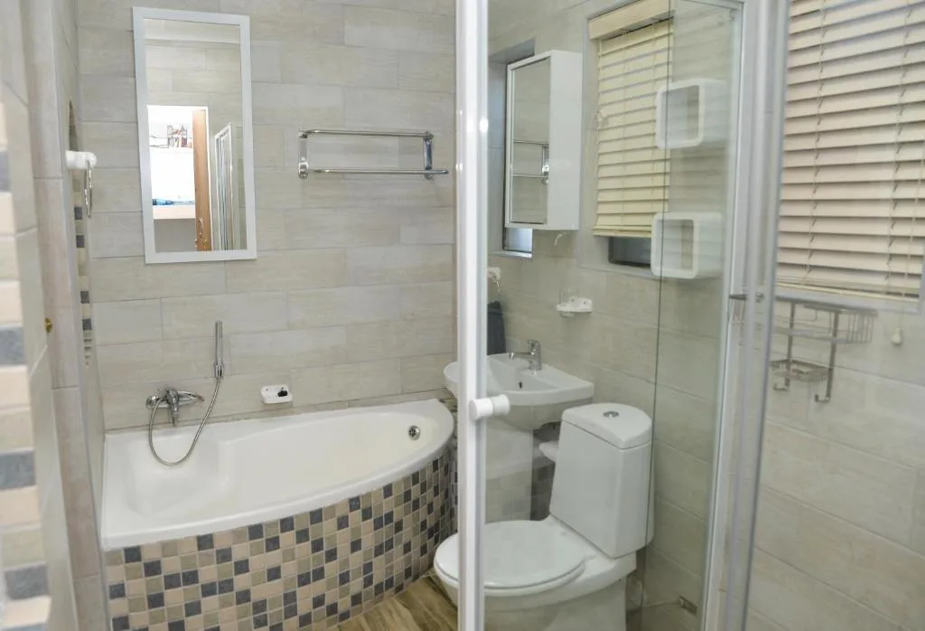 Modern bathroom with curved bathtub, shower enclosure, and toilet facilities