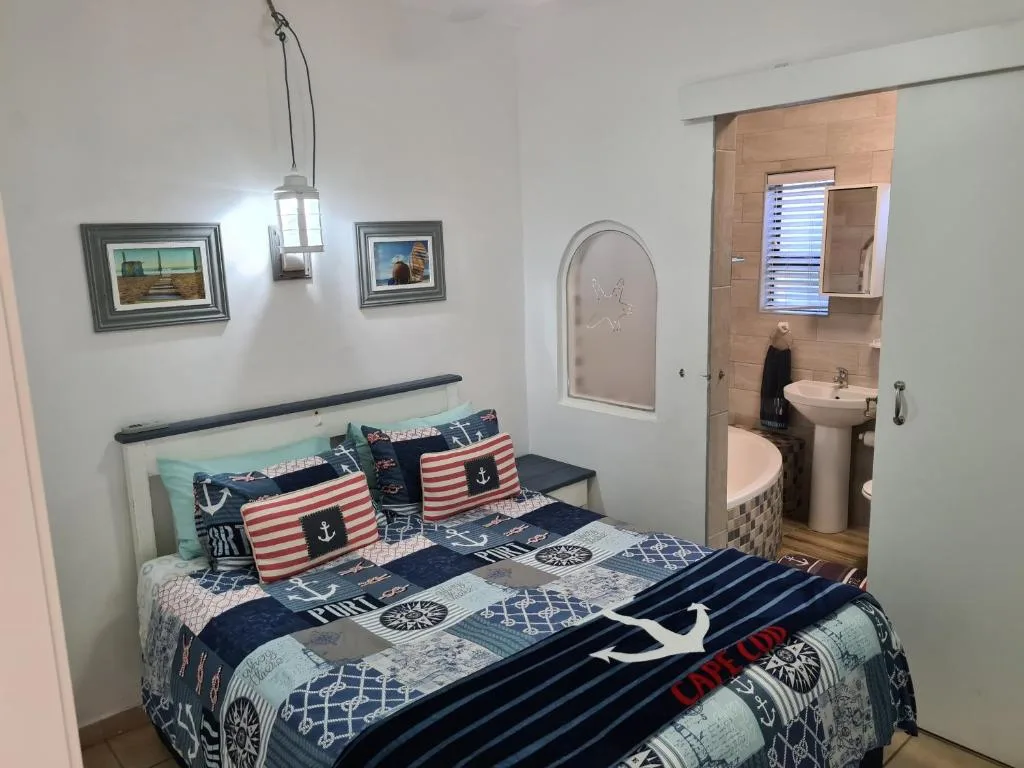 Nautical-themed bedroom with double bed and ensuite bathroom doorway visible