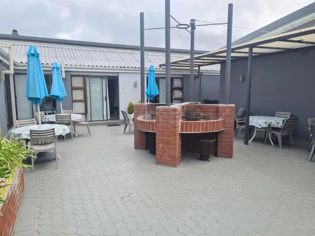 Spacious patio with brick braai, umbrellas, and seating areas