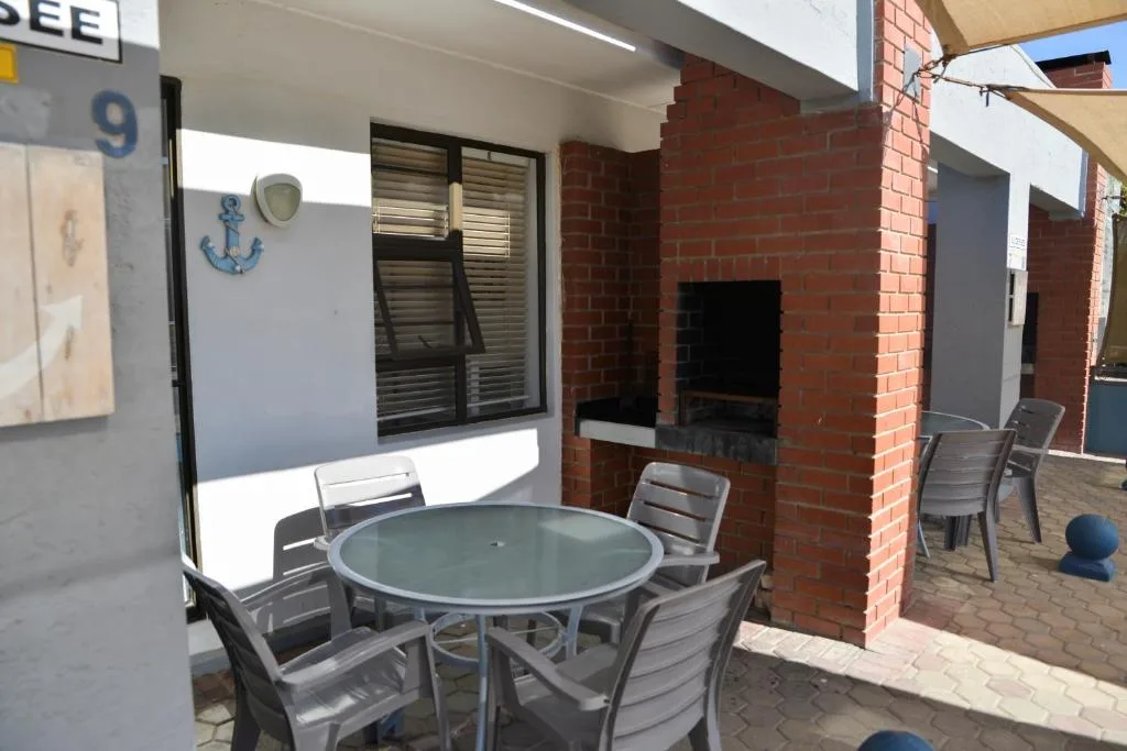 Outdoor patio with round table, chairs, and brick fireplace structure