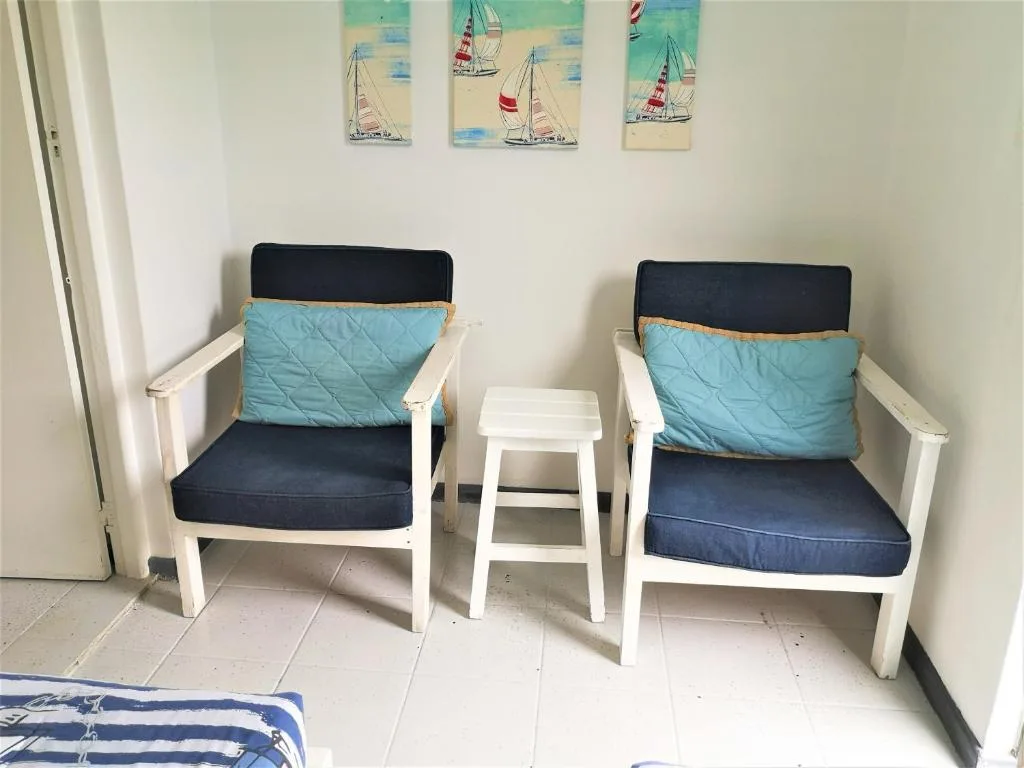 Two white wooden chairs with blue cushions and nautical sailboat artwork
