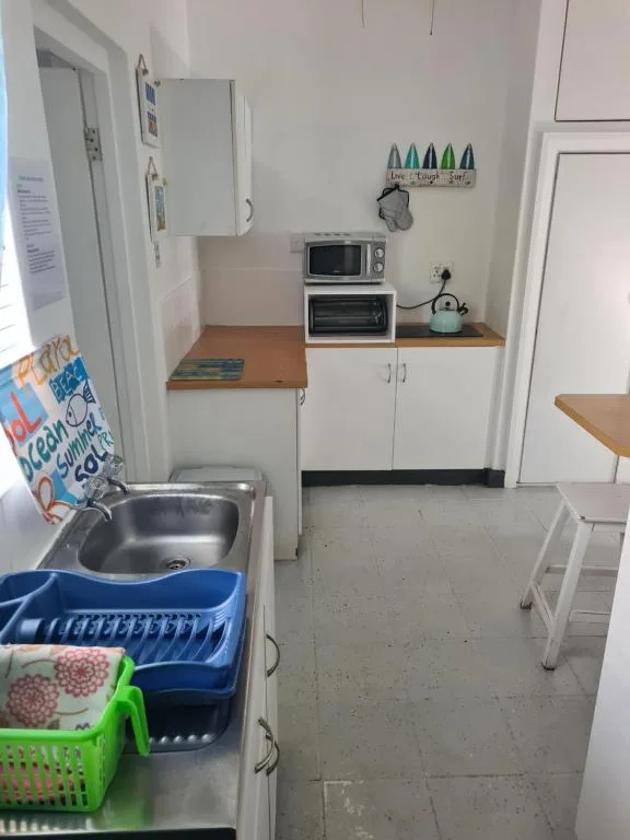 Compact kitchen with sink, microwave, and white cabinetry storage