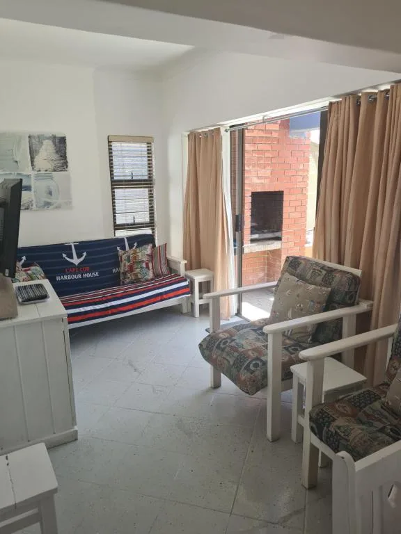 Bright lounge with nautical-themed sofa, armchairs, and glass doors to deck