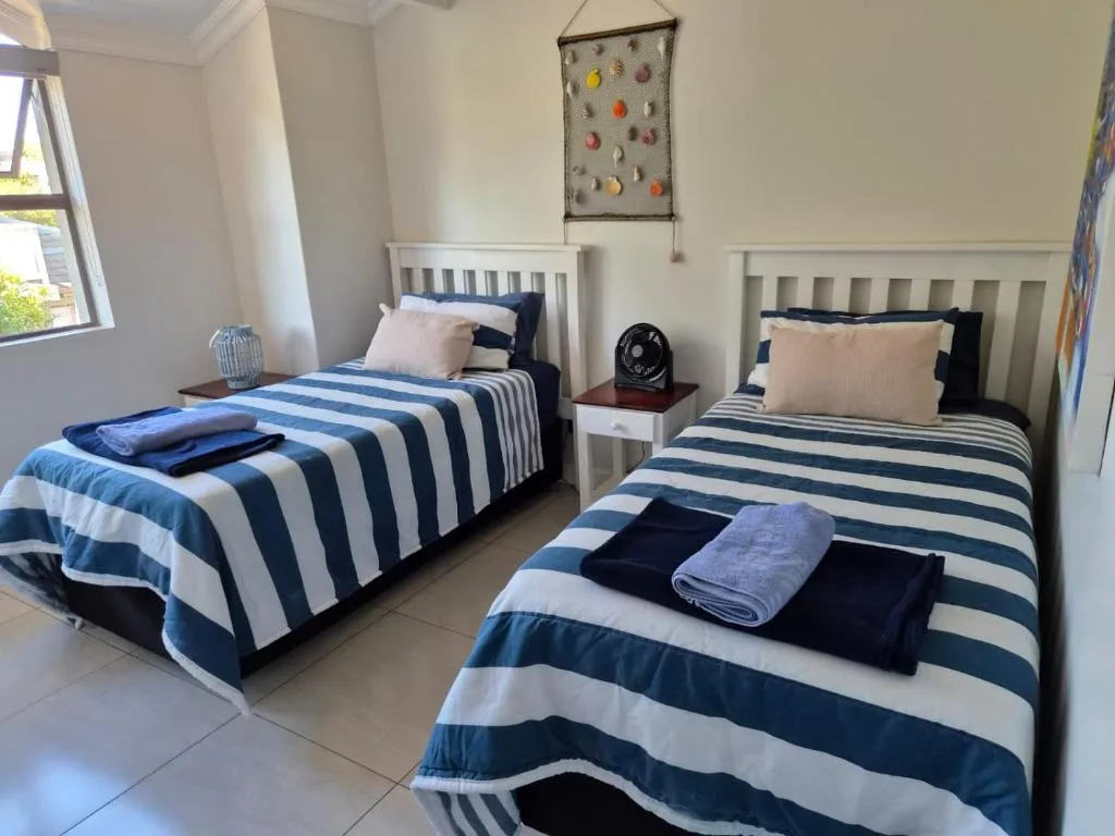 Twin bedroom with blue striped bedding and white wooden headboards