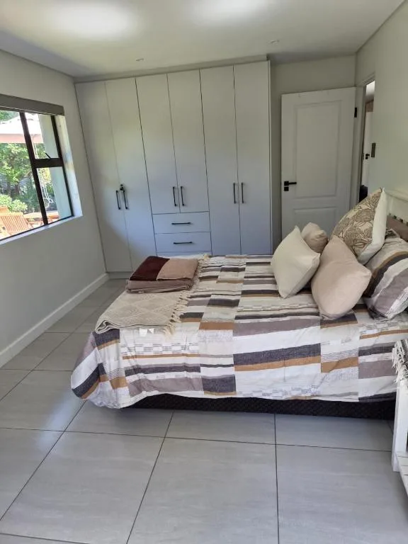 Bright bedroom with large bed, striped bedding, built-in wardrobes, window view