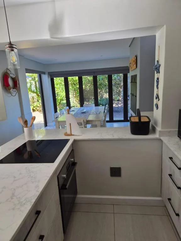 Modern kitchen with marble counters overlooking garden through large windows