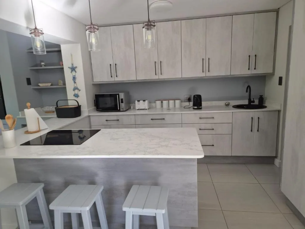 Modern kitchen with marble countertops, white cabinetry, and pendant lighting