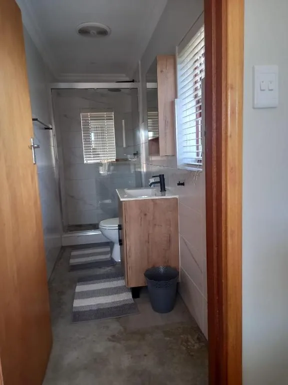 Modern bathroom with wooden vanity, walk-in shower, and toilet
