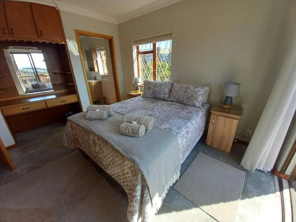 Spacious bedroom with double bed, rolled towels, wooden furniture and garden views