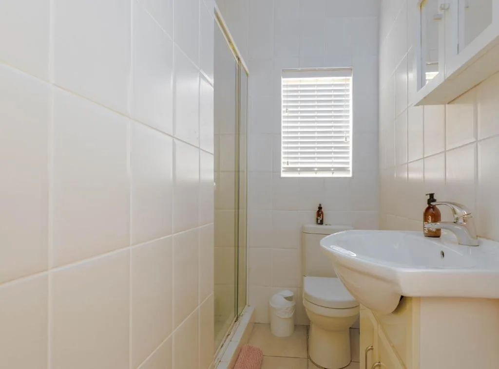 Clean bathroom with white sink, toilet, and glass shower enclosure