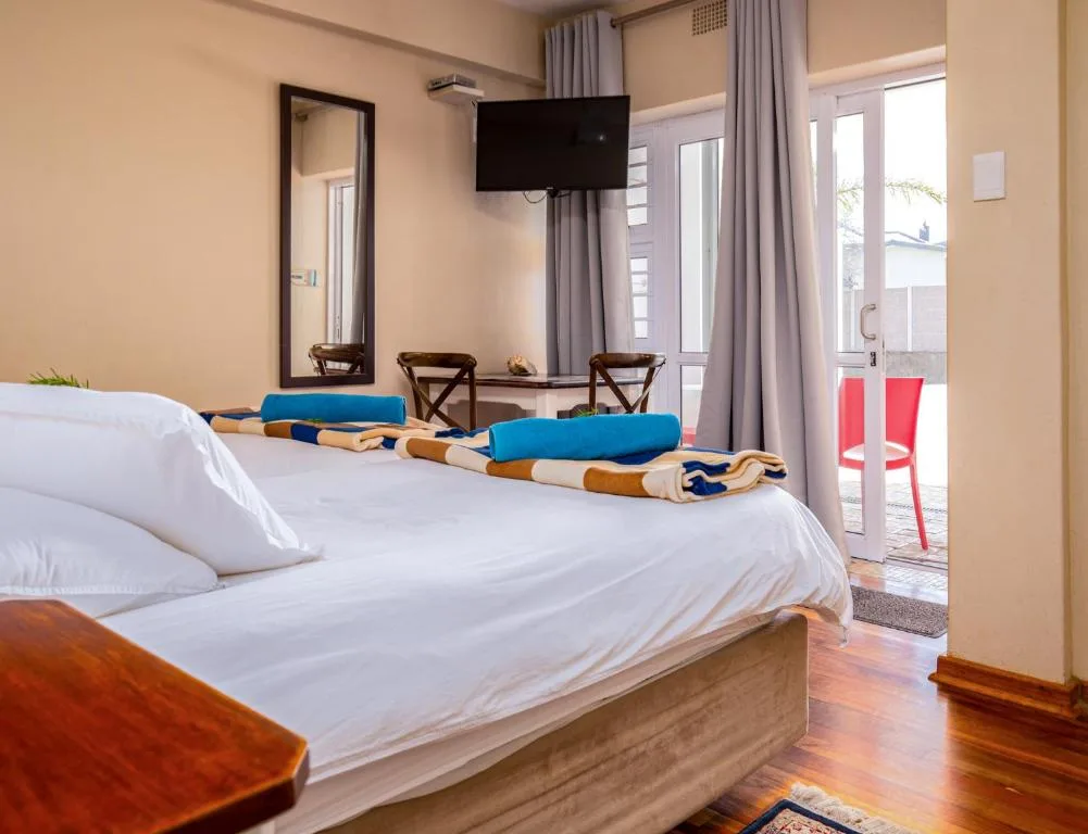 Spacious bedroom with white linens, wood bed frame, and open deck access