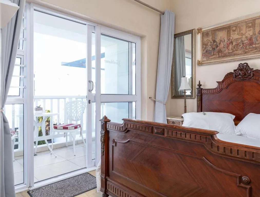 Bedroom with wooden bed frame overlooking ocean view through glass doors
