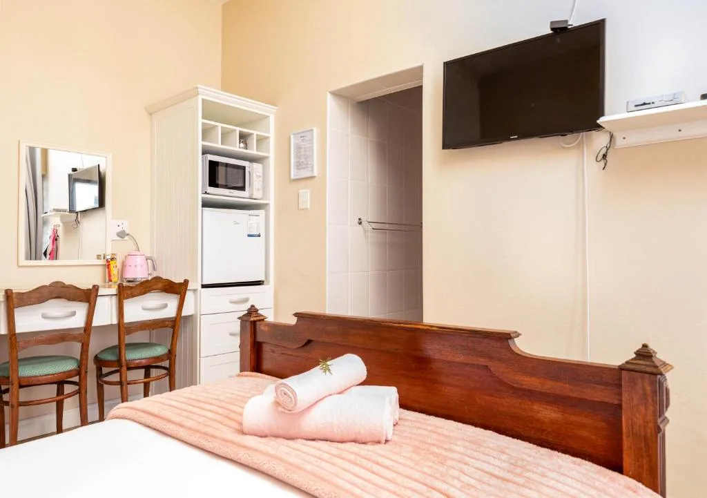 Studio bedroom with wooden bed frame and kitchenette facilities
