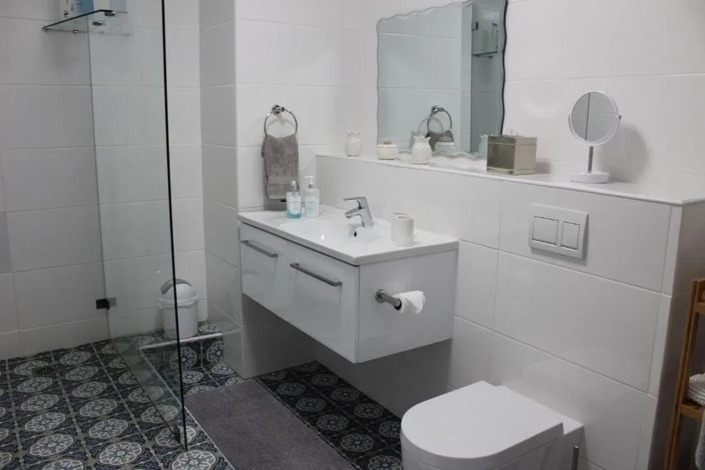 Modern bathroom with white vanity, rainfall shower, and patterned floor tiles