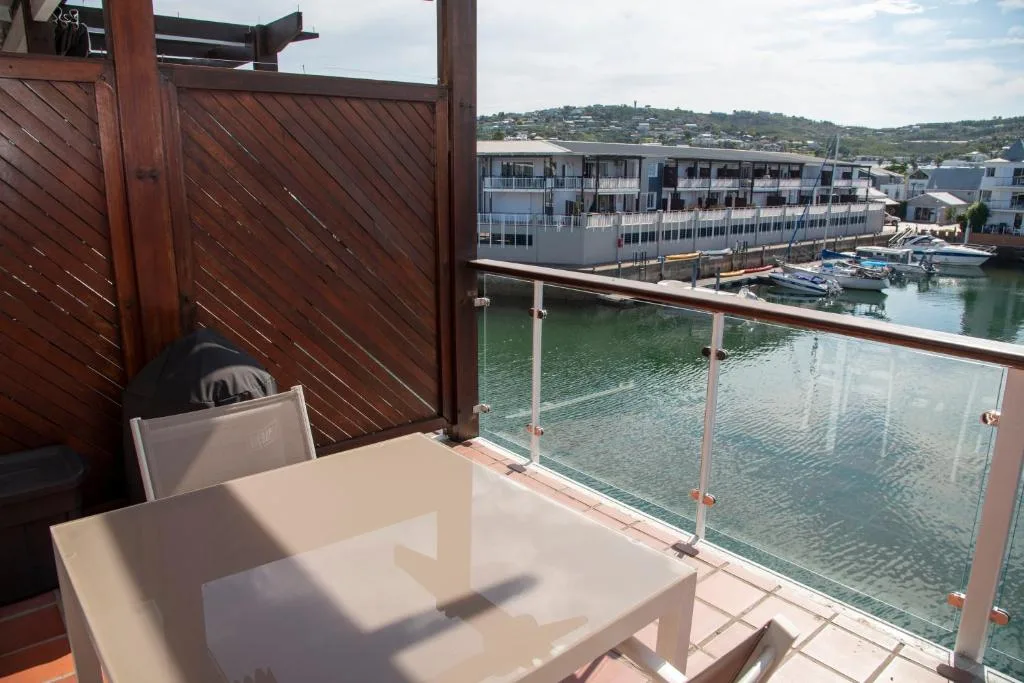 Waterfront deck with dining table overlooking Knysna lagoon and boats