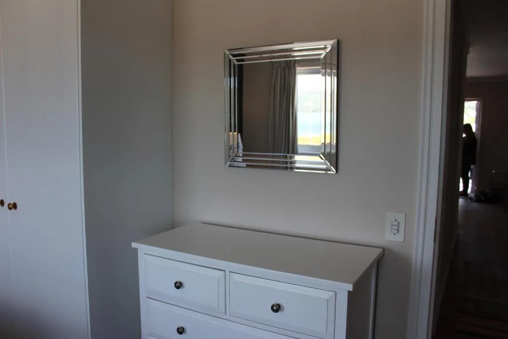 White dresser with mirror reflecting ocean view through window