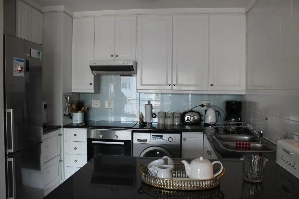 Modern kitchen with white cabinetry, black countertops, and stainless steel appliances