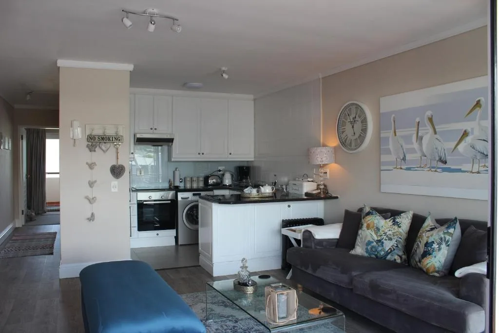 Open-plan lounge with dark sofa, blue accent chair, and integrated kitchen area