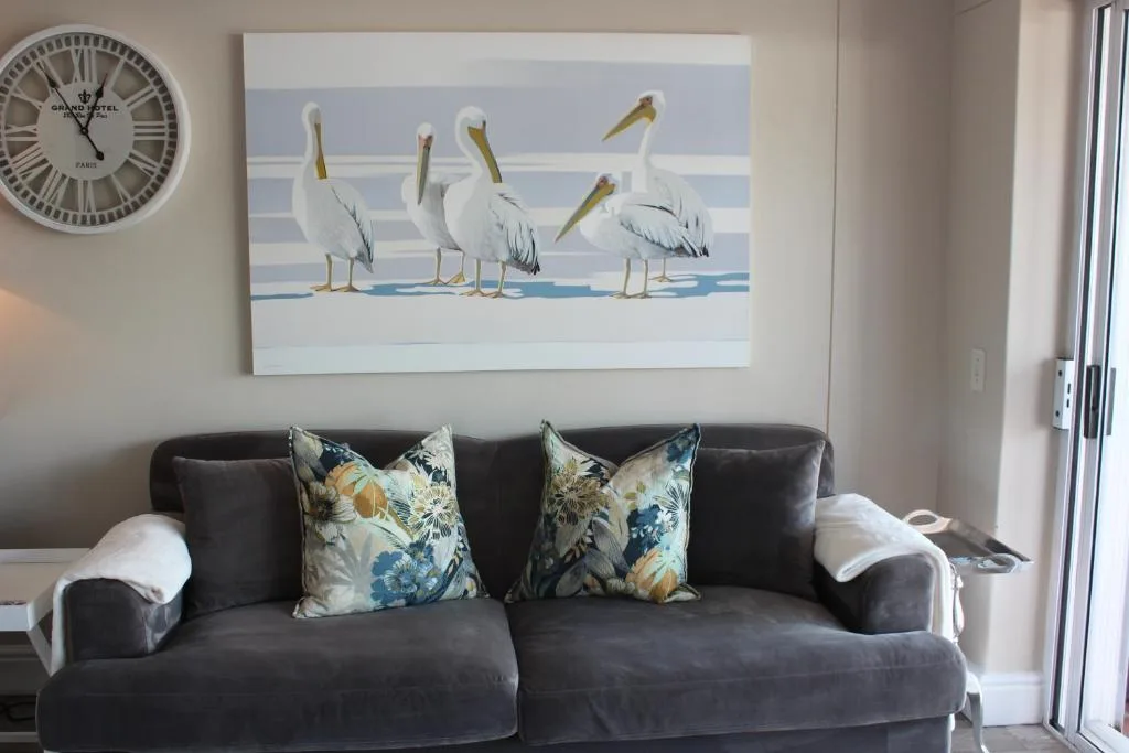 Modern lounge with dark sofa, decorative pelican artwork, and coastal decor