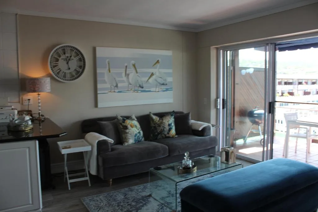 Modern lounge with dark sofa, coastal artwork, and sliding doors to deck
