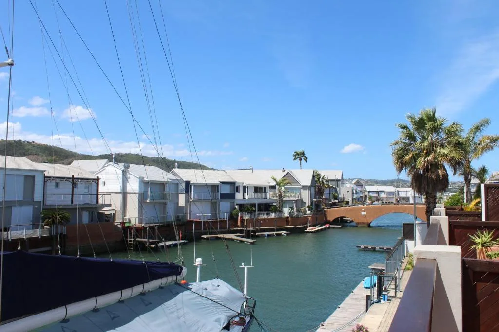 Waterfront canal with moored boats and colorful boathouses under blue sky