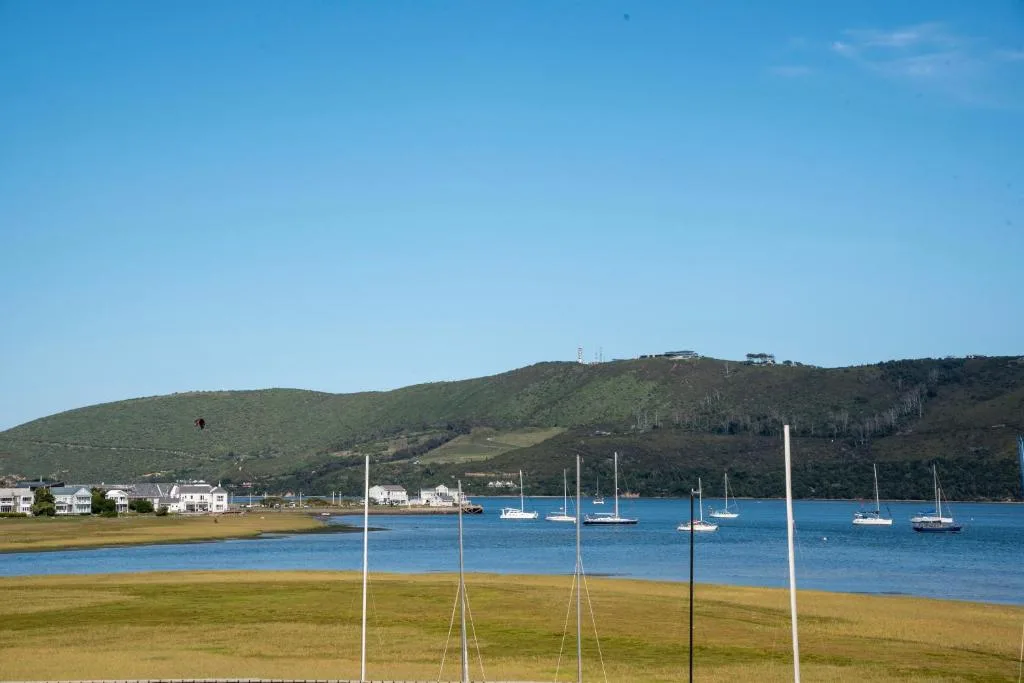 Scenic coastal view of Knysna lagoon with sailboats and green hills