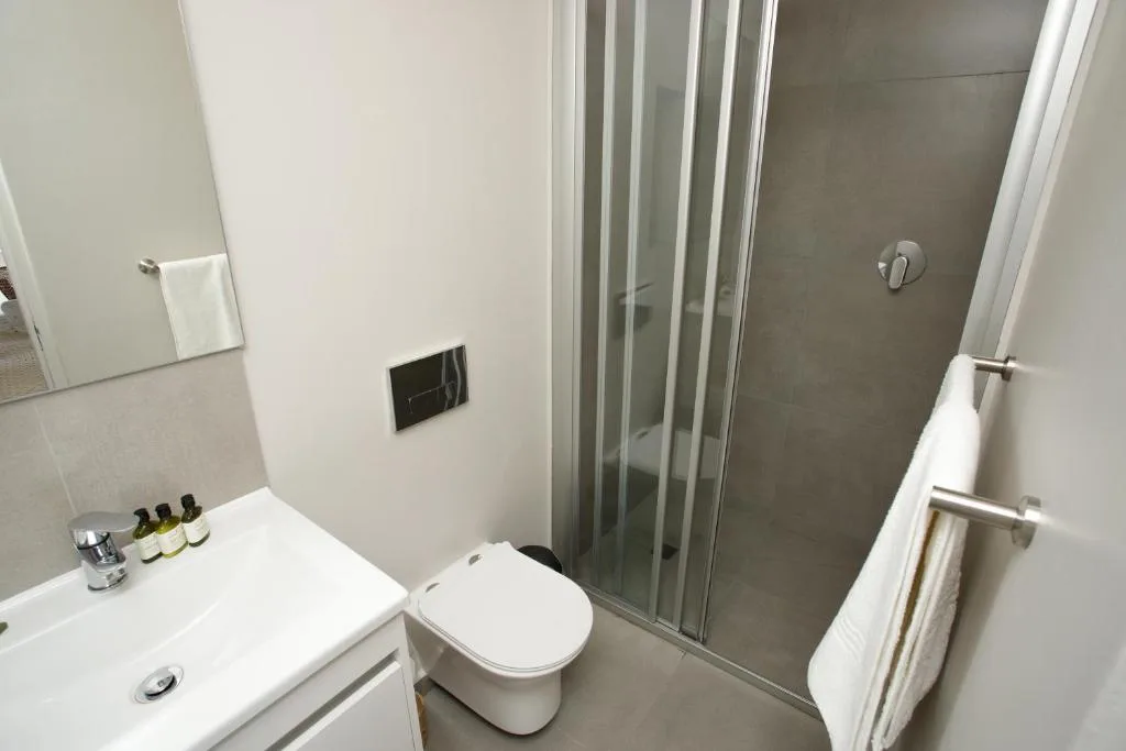 Modern bathroom with white vanity, toilet, and enclosed shower stall