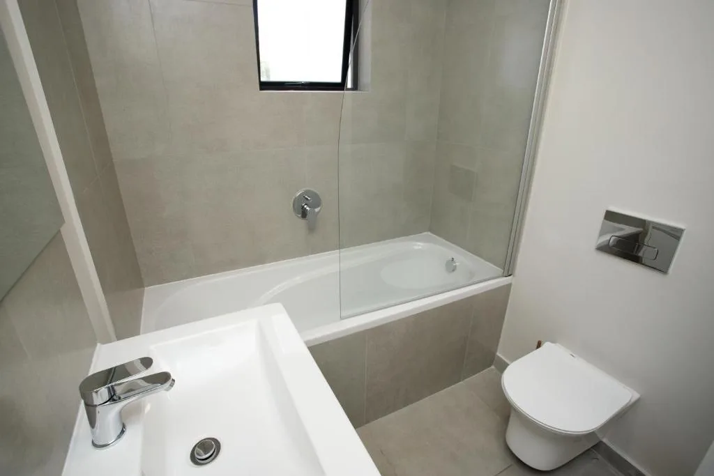 Modern bathroom with white basin, toilet, and glass-enclosed bathtub shower
