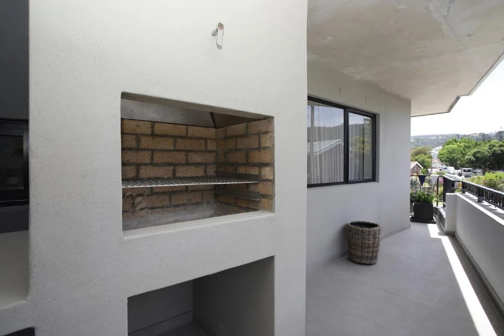 Outdoor patio area with built-in braai, wicker basket, and garden views