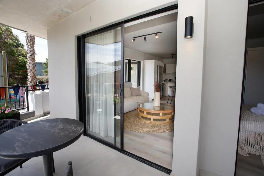 Covered patio with round table overlooking open-plan lounge interior