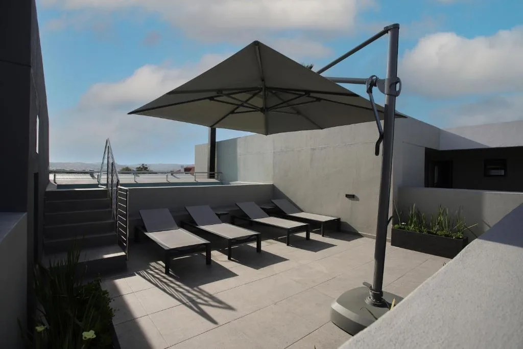 Modern rooftop deck with loungers, cantilever umbrella, mountain views