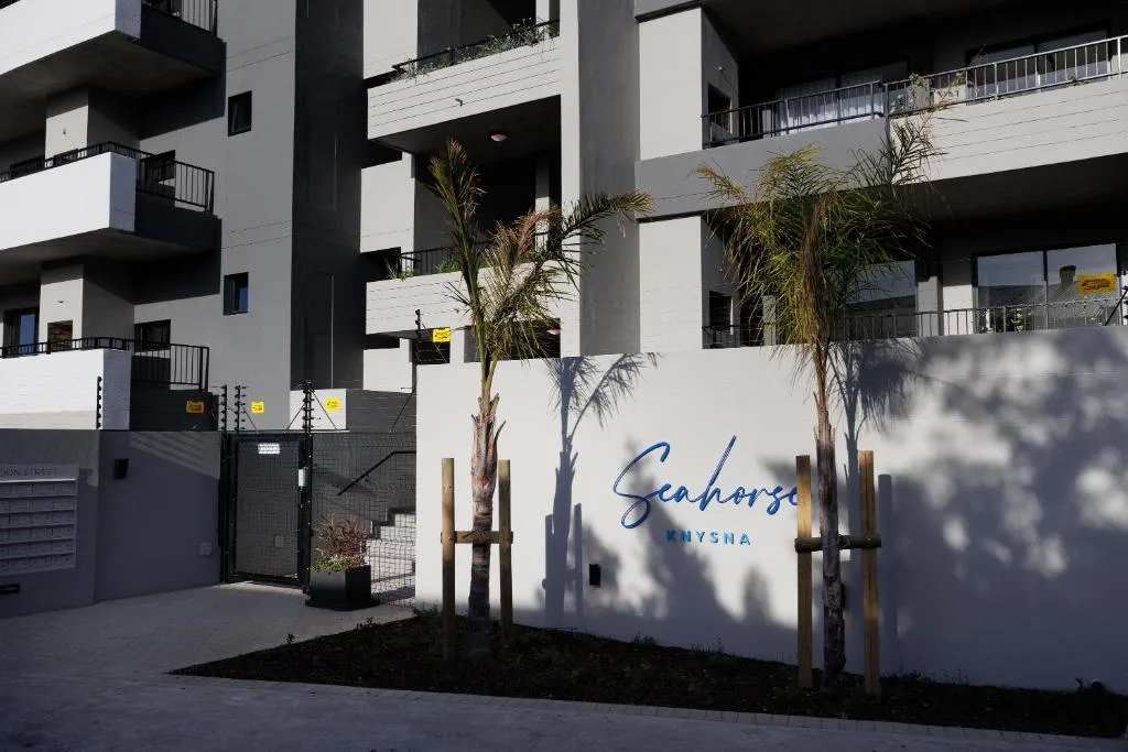 Modern white apartment building with Seahorse branding and palm trees entrance