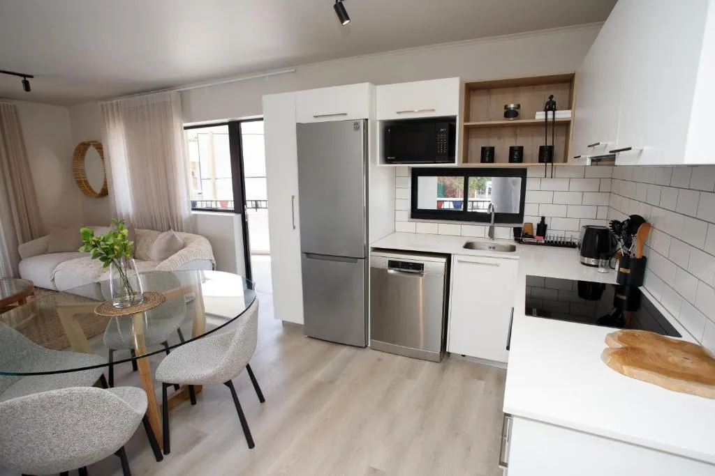 Modern open-plan kitchen with white cabinetry, stainless steel appliances, and subway tile backsplash