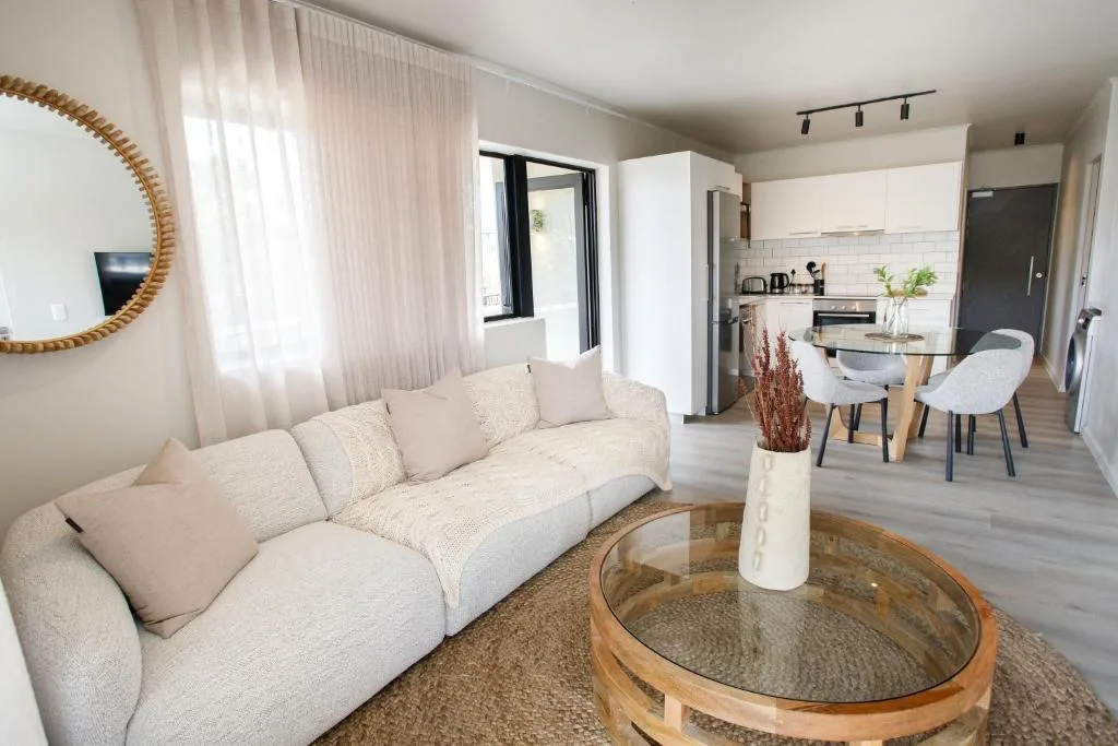 Bright open-plan lounge with cream curved sofa and round wooden coffee table