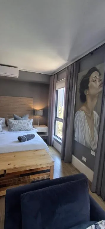 Modern bedroom with queen bed, grey walls, and portrait artwork on wall