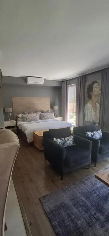 Modern bedroom with queen bed, dark accent chairs, and contemporary artwork
