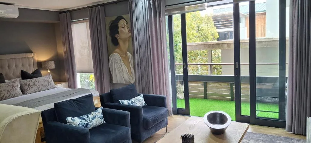 Modern bedroom with seating area and sliding doors to green garden deck