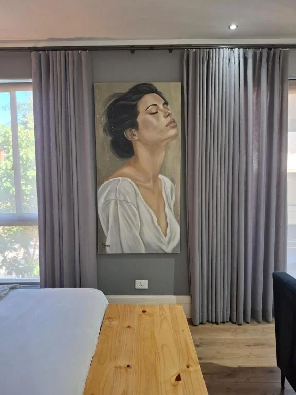 Modern interior with portrait artwork, floor-to-ceiling curtains, wooden table