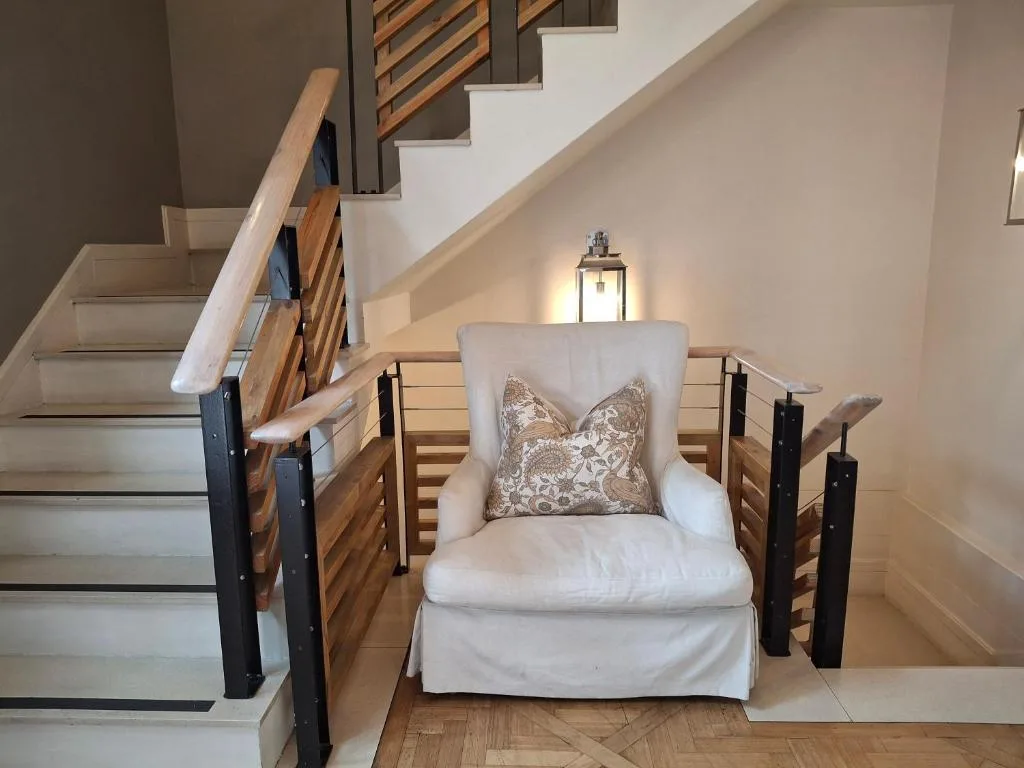 Elegant cream armchair with decorative pillow positioned under staircase landing