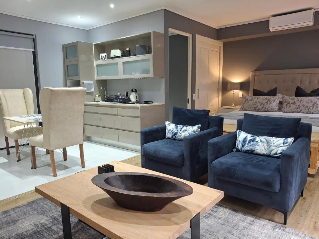 Modern lounge with navy armchairs, wooden coffee table, and kitchenette area