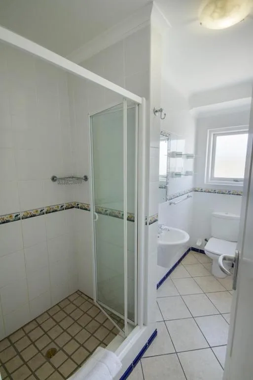 Clean bathroom with shower enclosure, sink, toilet, and tiled flooring