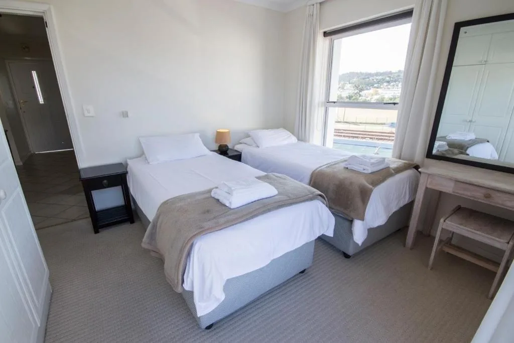 Spacious bedroom with three single beds, white linens, and lagoon views